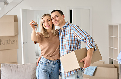 happy couple holding keys and cardboard box in new home moving in 8 keys to success