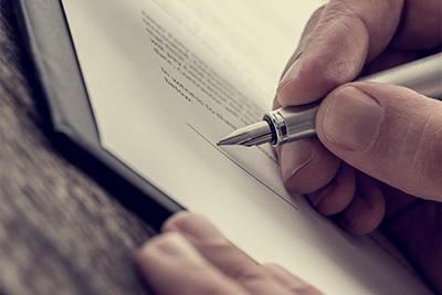 hand holding a silver pen signing a document with a focus on the signature area related to important agreements and 15 key points